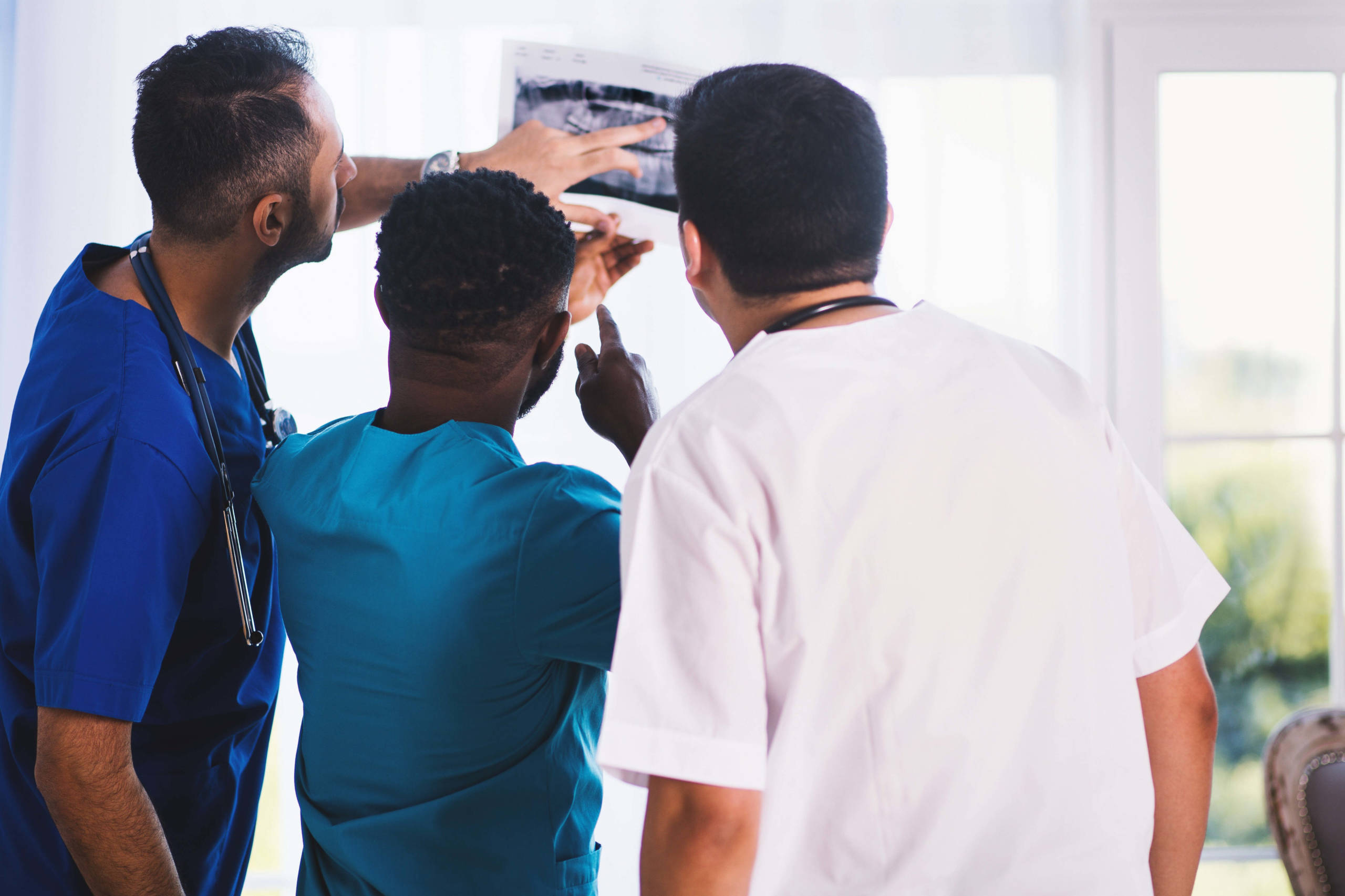 three people in scrubs looking at x ray results