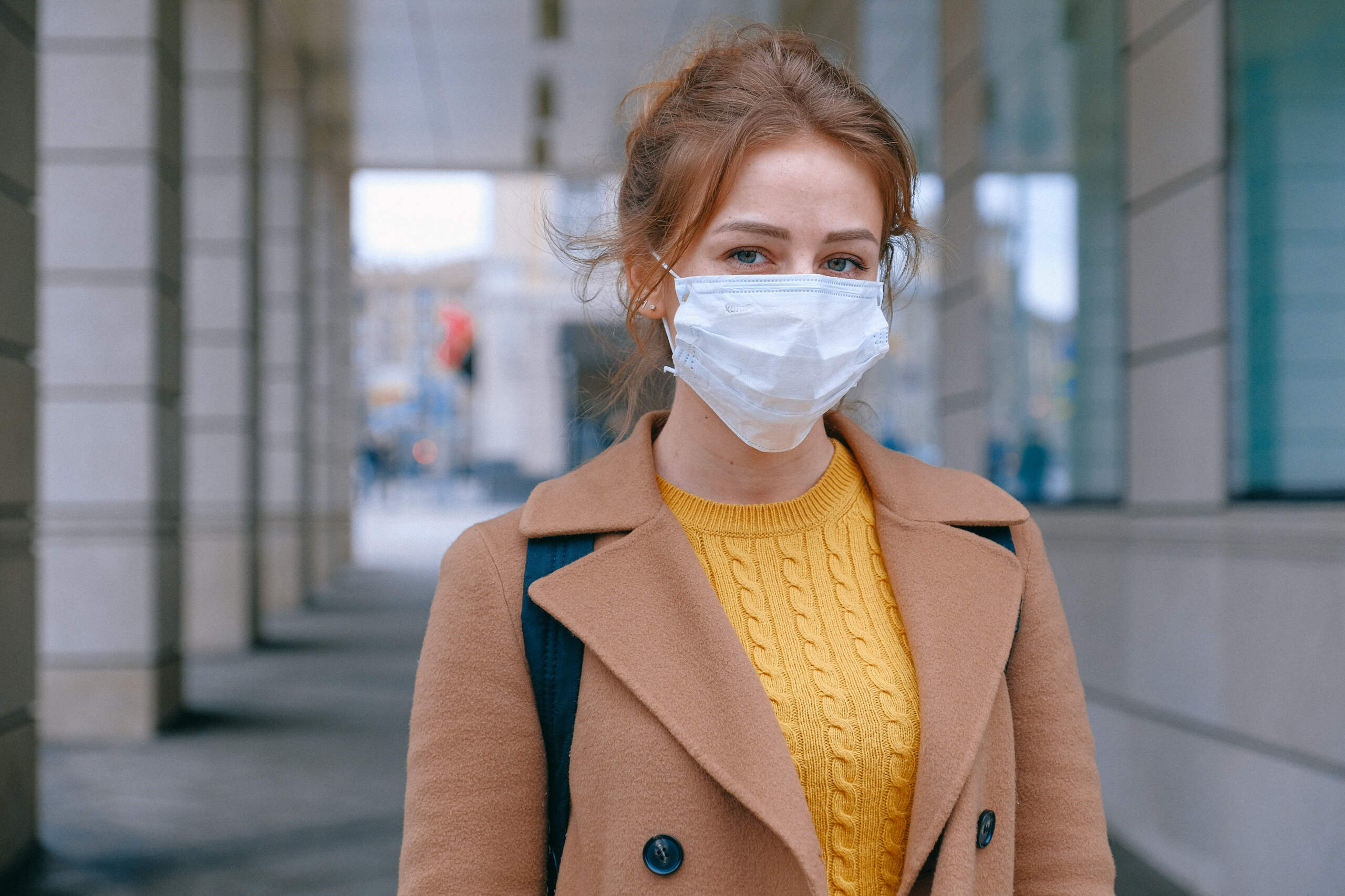Photo of woman in winter coat wearing white surgical mask