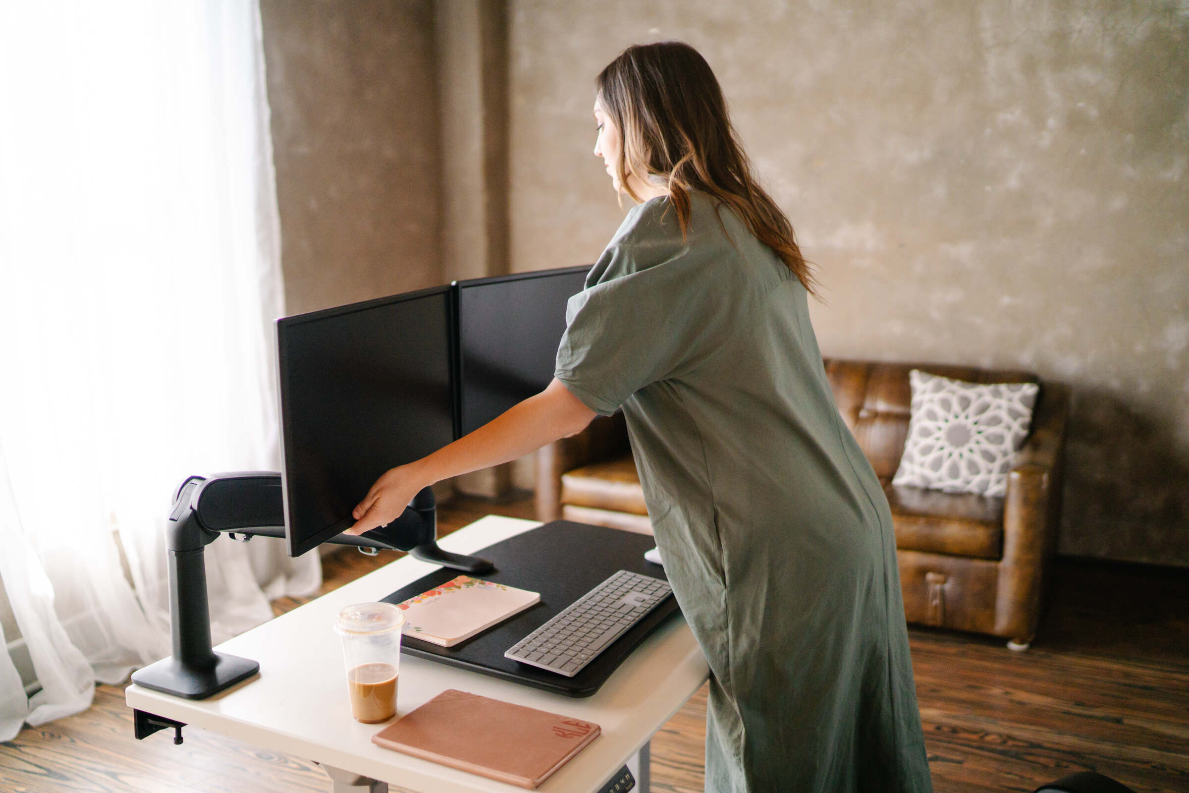 woman with her standing desk realizing the benefits of an anti-fatigue mat